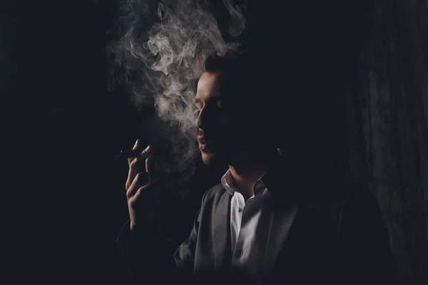 Attractive young man with cigar and smoke on black background — Stock Photo, Image