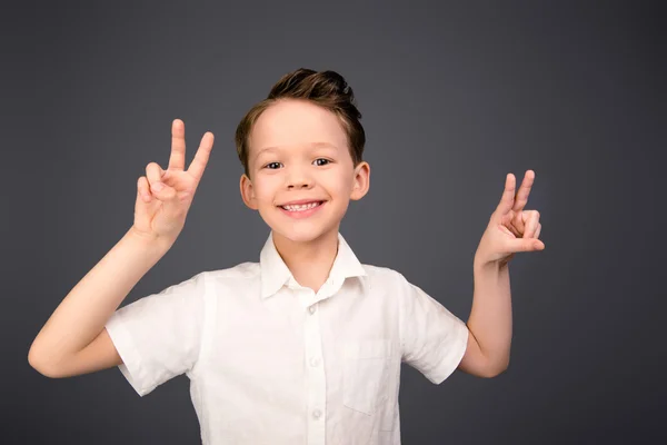 Glada leende komiska pojke gestikulerande med två fingrar — Stockfoto