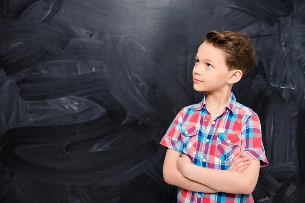 Ung pojke med korsade händer nära svarta tavlan i skolan — Stockfoto