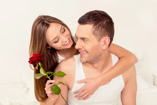 Linda pareja feliz en el amor abrazando y sosteniendo rosa roja — Foto de Stock