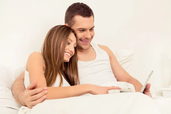 태블릿의 침대에 앉아 사랑에 귀여운 커플의 초상화 — 스톡 사진