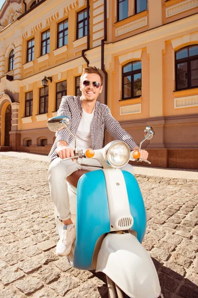 Przystojny mężczyzna ładny w okularach siedzący na skuter na ulicy — Zdjęcie stockowe