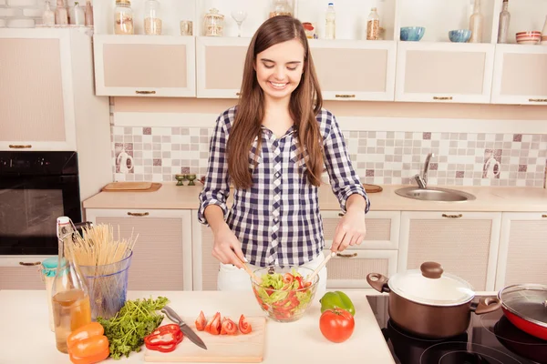 Portret van vrolijke jonge vrouw koken en salade mengen — Stockfoto