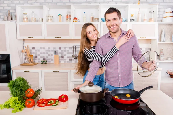 Gelukkig jonge man en vrouw knuffelen en koken in de keuken — Stockfoto
