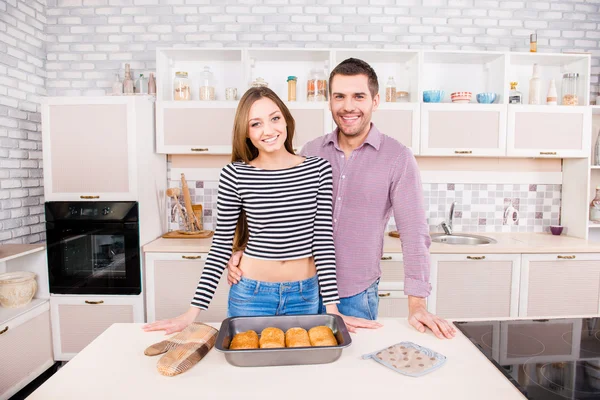 Smilling unga par i kärlek i köket med bakade kakor — Stockfoto