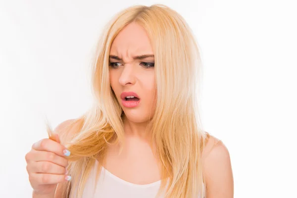 Sad pretty girl looking at her damaged hair — Stock Photo, Image