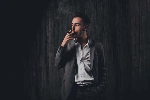 Retrato de un joven serio en traje fumando un cigarrillo — Foto de Stock