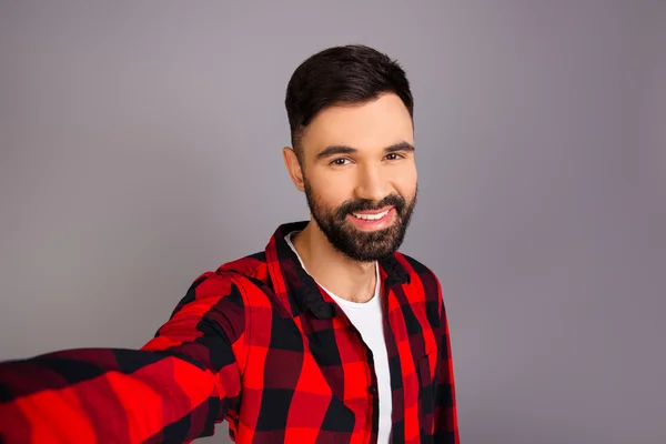 Succesvolle bebaarde gelukkig man in een rood shirt maken selfie — Stockfoto