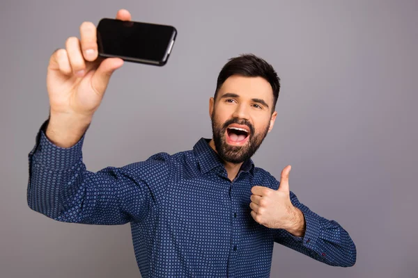 Jovem feliz fazendo selfie engraçado e mostrando o polegar para cima — Fotografia de Stock