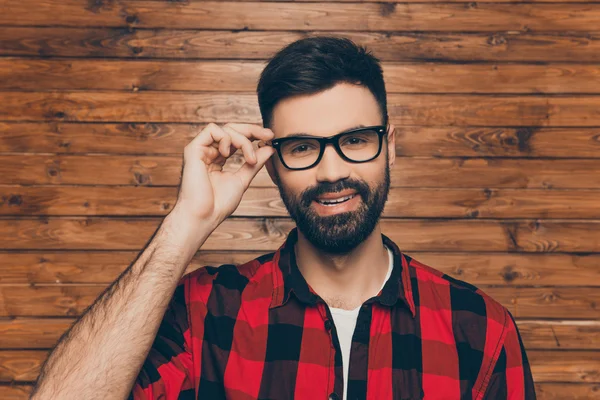 Красивый молодой улыбающийся мужчина трогает свои очки — стоковое фото