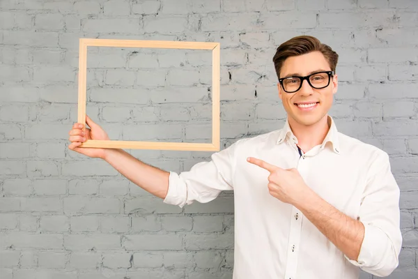 Jóképű férfi szemüveg mutat a fa keret a kezében — Stock Fotó