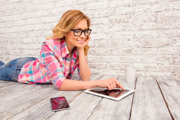 Mujer atractiva en gafas tumbadas en el suelo y tocando la pantalla o —  Fotos de Stock