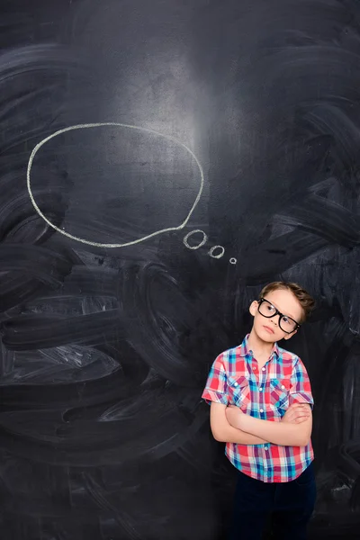 Young child on the background of chalkboard thinking about smth — Stock Photo, Image