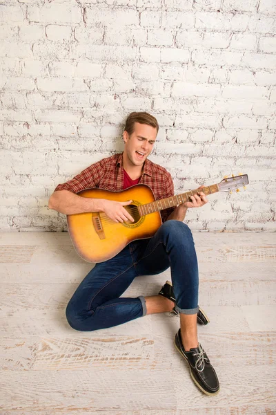 Jonge muzikant aanbrengen op de vloer met gitaar en zang — Stockfoto