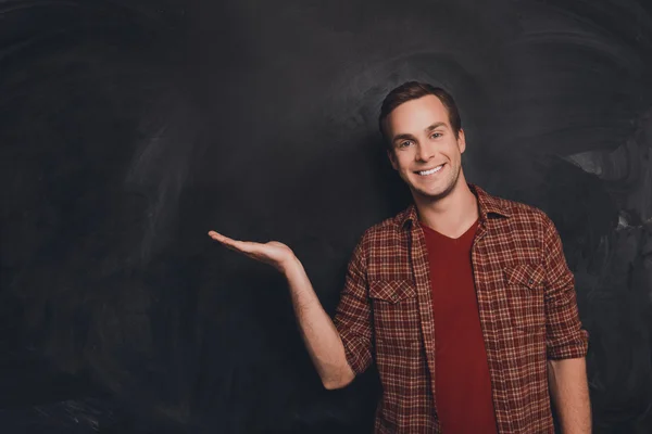 Smiling young man offering a product on  background of chalkboar — Stock Photo, Image