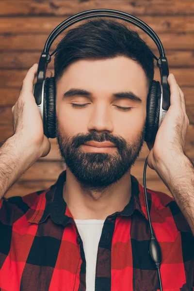 Joven relajado en los teléfonos de la cabeza escuchando música con los ojos cerrados — Foto de Stock
