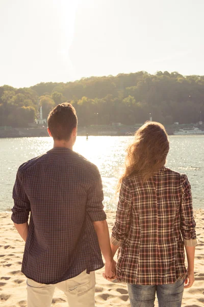 Hipster giovane coppia innamorata tenendosi per mano al mare — Foto Stock