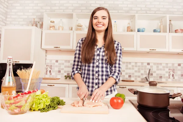 Mooie lachende huisvrouw koken diner en vlees snijden — Stockfoto