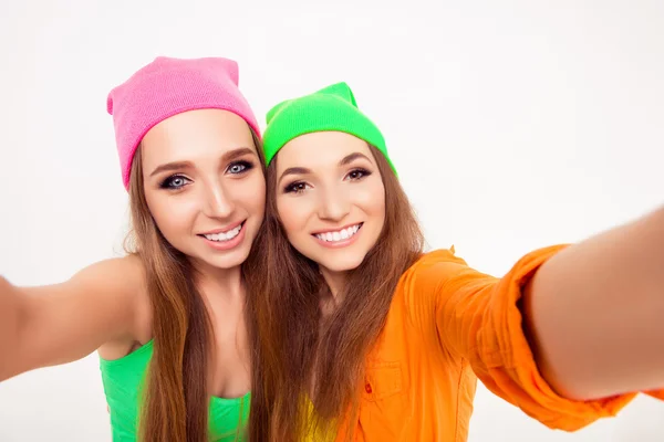 Счастливые улыбающиеся девушки в цветных шляпах делают селфи — стоковое фото
