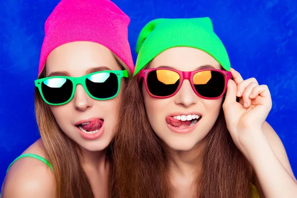 Portrait de deux jolies sœurs en chapeaux et verres montrant tongu — Photo