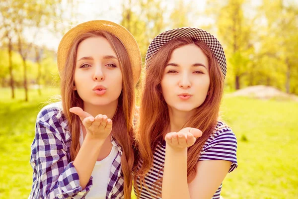 Portrait of beautiful girls in hats sending airy kiss — Stock Photo, Image