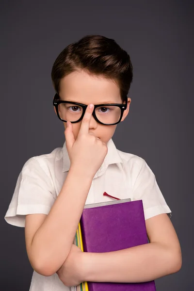 Smart liten skola pojke i glas håller böcker — Stockfoto