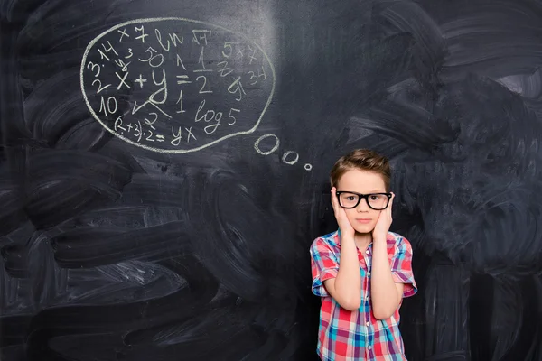 Portrait of young schoolboy in glasses trying to solve difficult — Stock Photo, Image