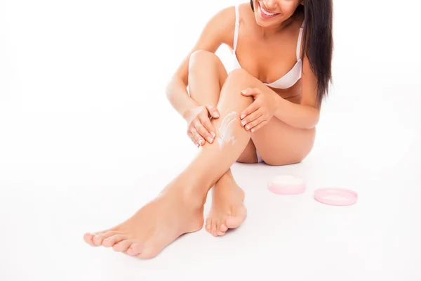 Foto da vicino della donna sorridente che applica la crema sulle gambe — Foto Stock
