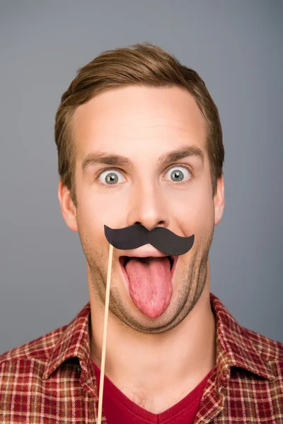 Närbild foto av man med papper mustasch visar tungan — Stockfoto