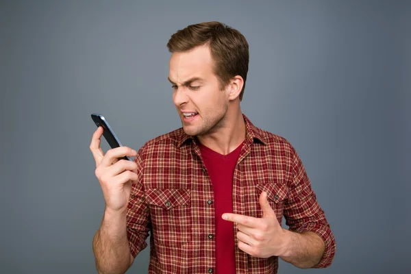 Sorprendido joven sosteniendo el teléfono y leyendo el mensaje —  Fotos de Stock