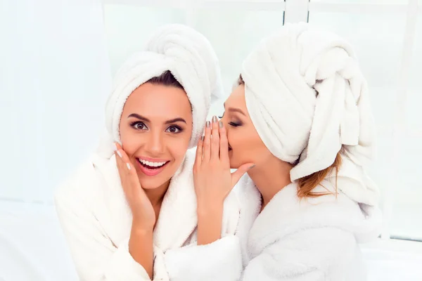 Girl in bathrobe and  towel on her head telling secret to her si — Stock Photo, Image