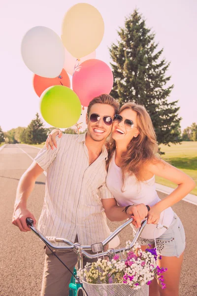 Portrait of cheerful pretty couple in love with bikes and balloo — Stock Photo, Image