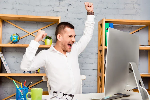 Fröhlicher, glücklicher junger Mann triumphiert mit erhobenen Händen — Stockfoto