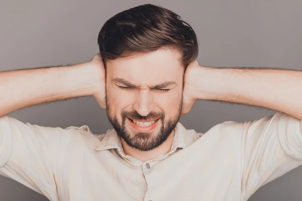 Перевантажений сумний чоловік, що має головний біль і прикриває вуха руками — стокове фото