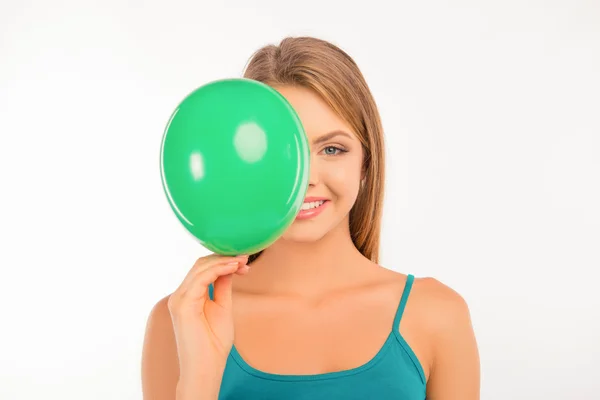 Happy cute girl hiding her face behind green balloon — Stock Photo, Image