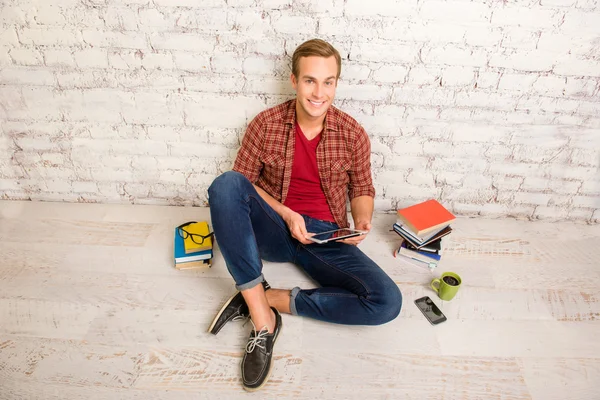 Alegre estudiante feliz sentado en el suelo con libros y tabletas —  Fotos de Stock