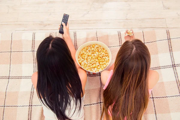 Крупним планом фото двох дівчат лежать на ліжку з попкорном — стокове фото