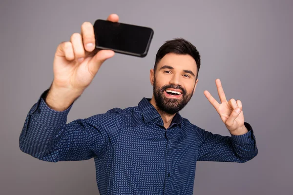 Selfie yapma ve iki parmak ile işaret mutlu genç adam — Stok fotoğraf