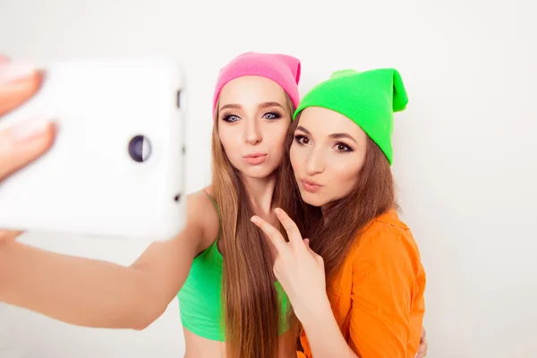 Hermosas hermanas hipster en gorras tomando fotos en el teléfono móvil — Foto de Stock