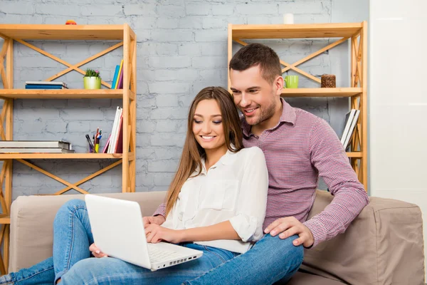 Boldog pár szerelmes ül a kanapén, laptop, és ezzel s — Stock Fotó