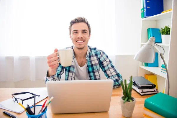 Homme souriant heureux de boire du café tout en travaillant sur un ordinateur portable — Photo