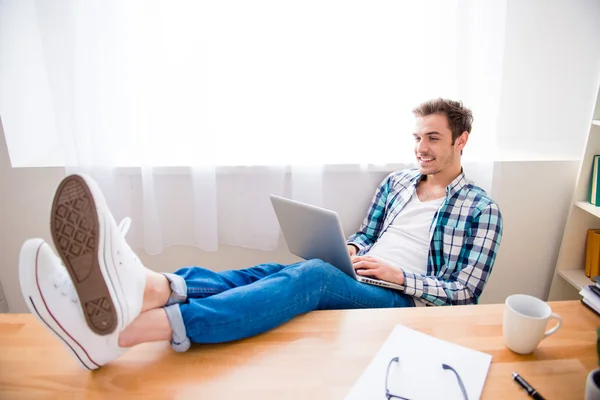 Jungunternehmer arbeitet am Laptop und hält Beine auf dem Tisch — Stockfoto