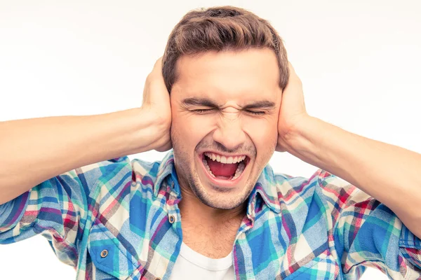 Jonge man die betrekking hebben op zijn oren en schreeuwen — Stockfoto