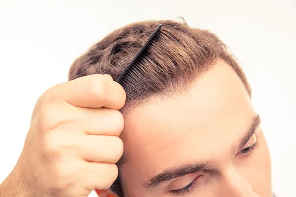 Foto close-up de belo jovem penteando seu cabelo — Fotografia de Stock