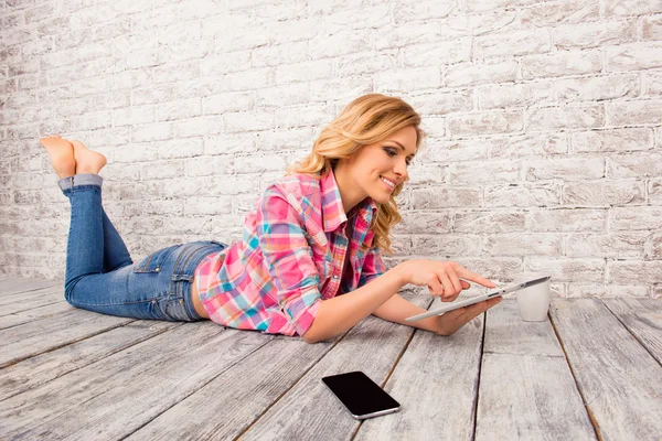 Красивая молодая женщина лежит на полу с планшетом и смартфоном — стоковое фото