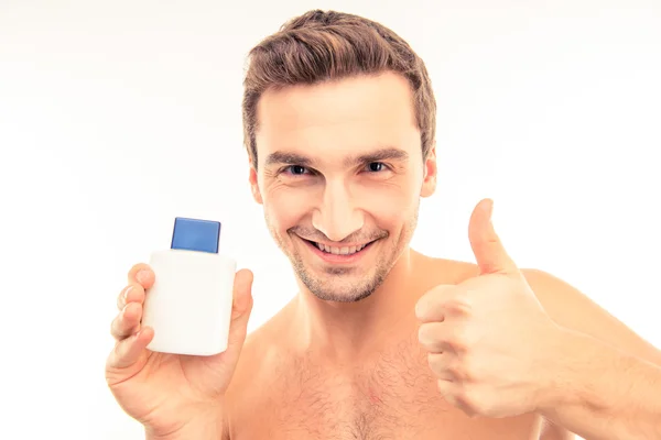 Pohledný mladý muž, držící krém po holení ukazuje palec — Stock fotografie