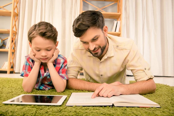 Tabletka vs książki. Ojciec i jego synek, czytanie — Zdjęcie stockowe