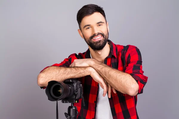 Cheerful happy young man standing with camera in studio — Stock Photo, Image