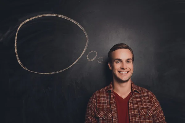 Handsome smiling young man having a mind about task — Stock Photo, Image