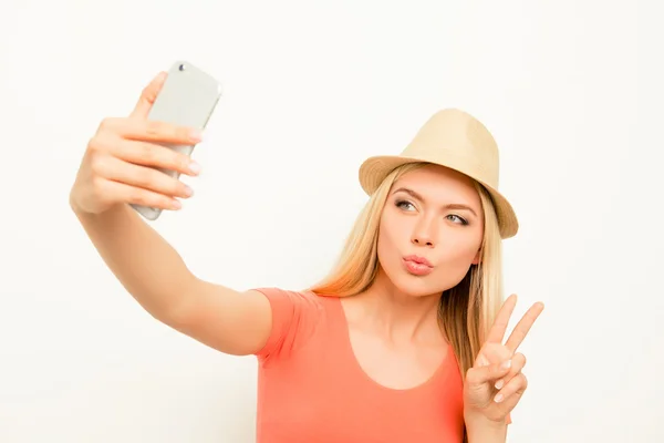 Frau mit Hut macht Selfie, schmollt und zeigt zwei Finger — Stockfoto